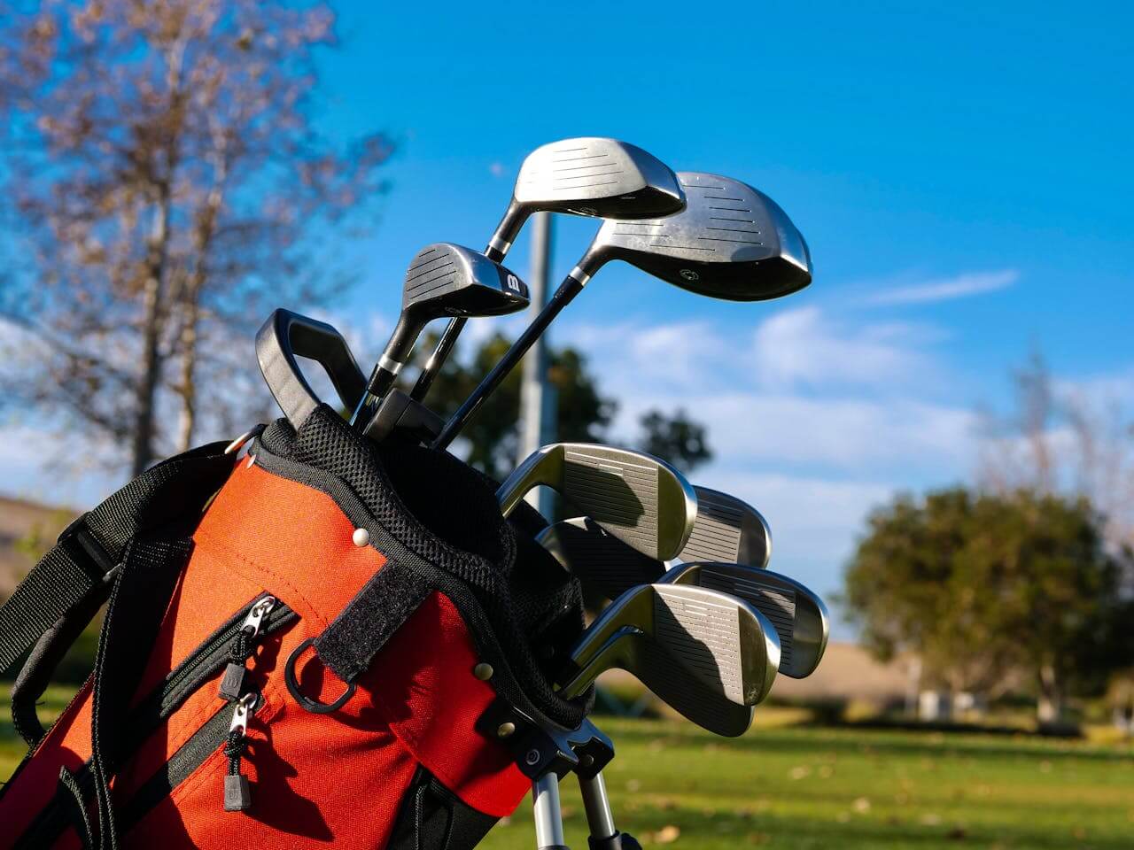 A set of golf clubs with a course in the background