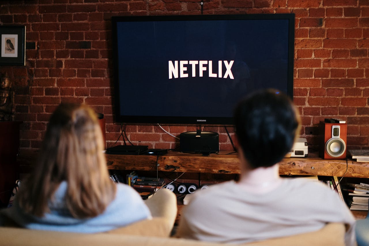A couple looking at their large TV screen with the Netflix logo on