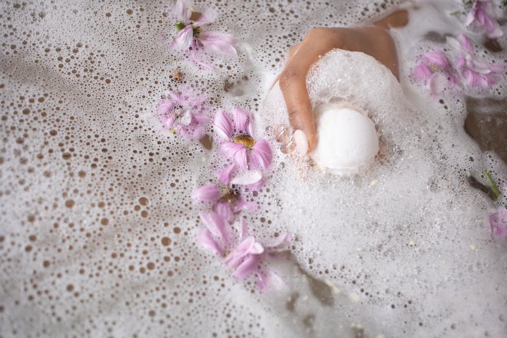A woman holding an organic bathroom product while having a bath