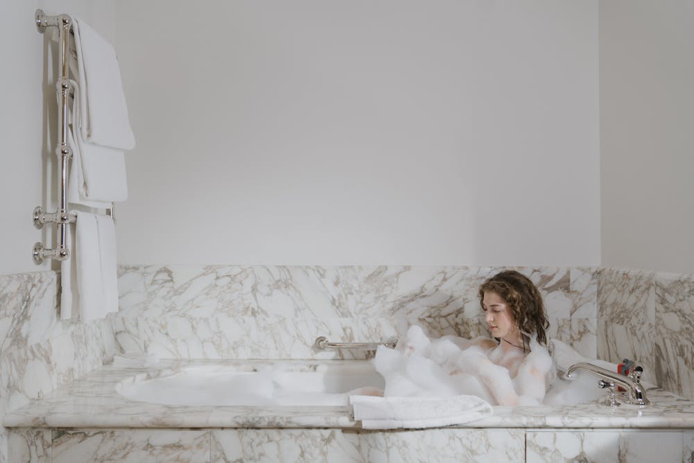 A woman having a bubble bath in a luxurious bathroom