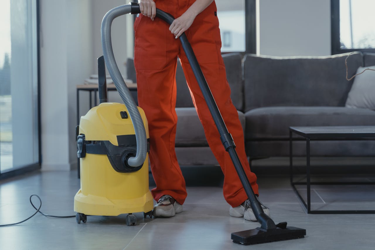 A house cleaning technician vacuuming a tiled living room floor