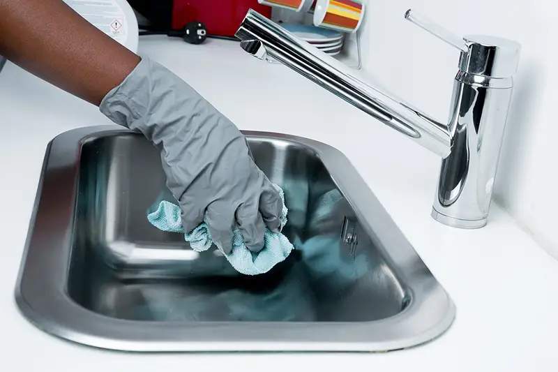 Cleaning Stainless Steel Sink with Pink Rubber Gloves