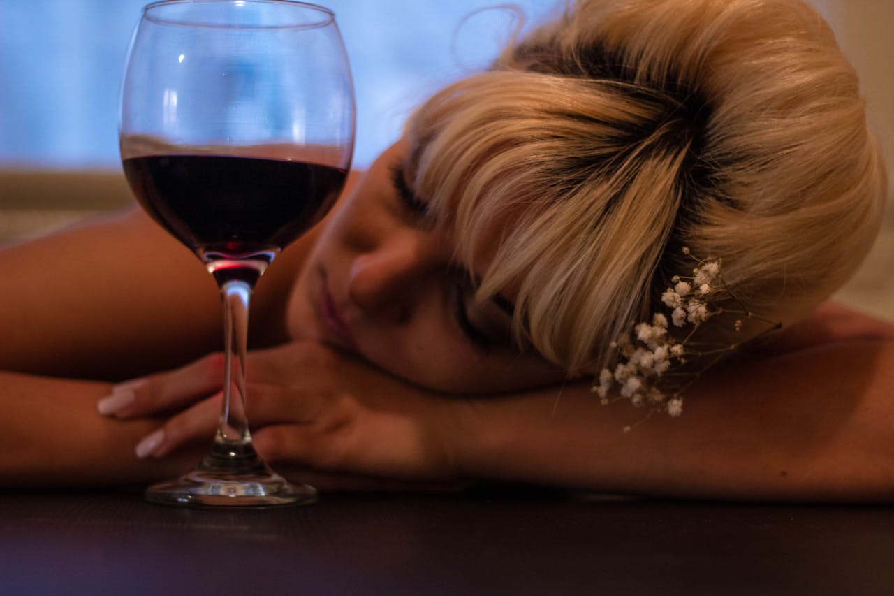 A sleeping woman next to a glass of red wine