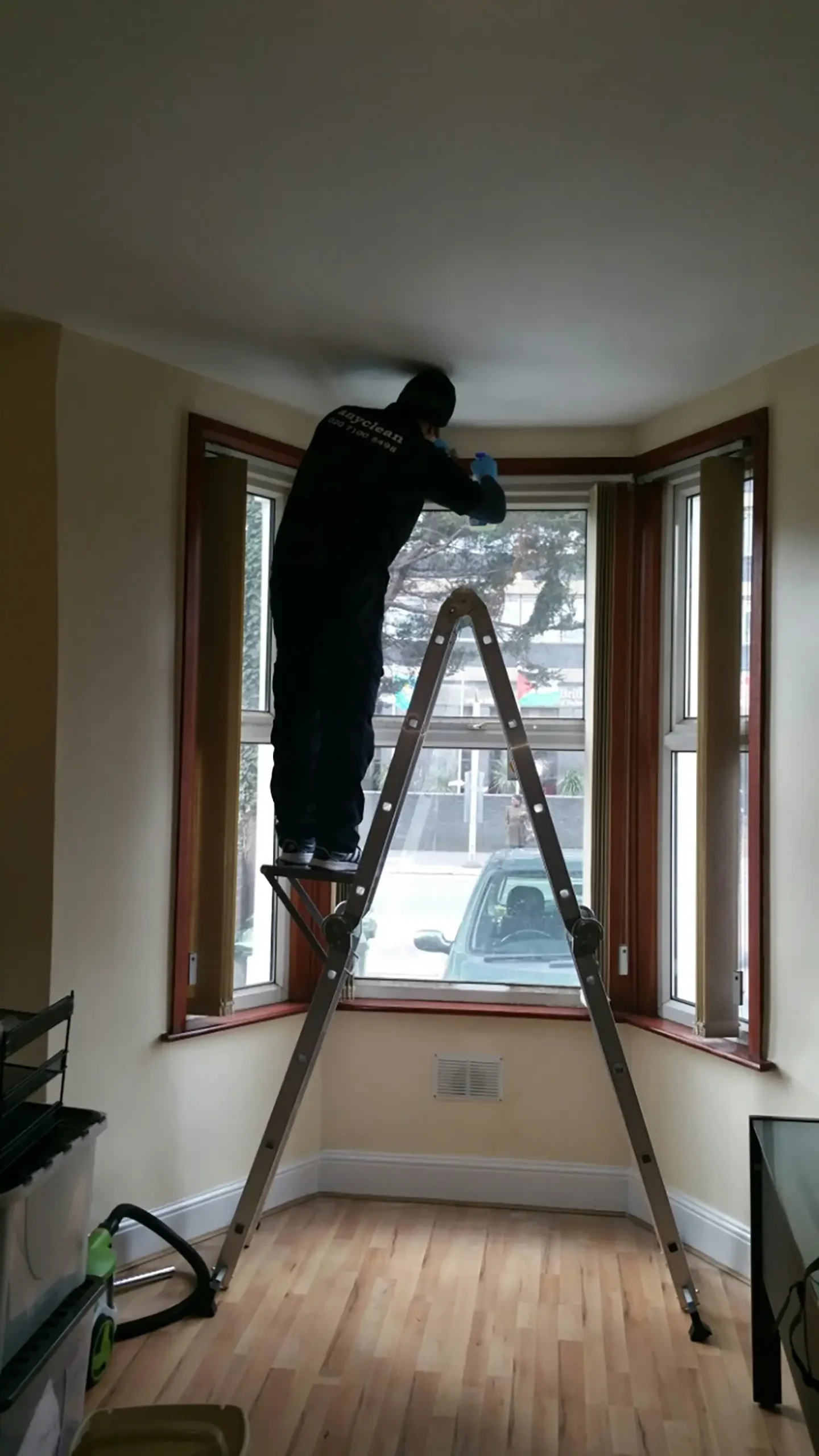 Anyclean Tenancy Technician Cleaning the Top of a Window Using a Ladder