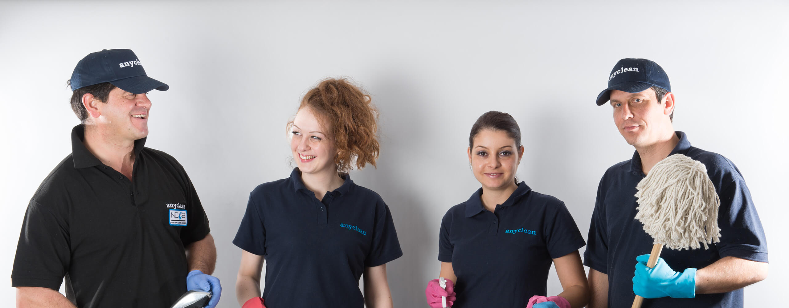Uniformed Anyclean cleaning professionals holding cleaning equipment