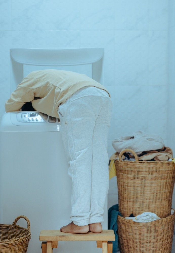 A woman picking up laundry from a washing machine